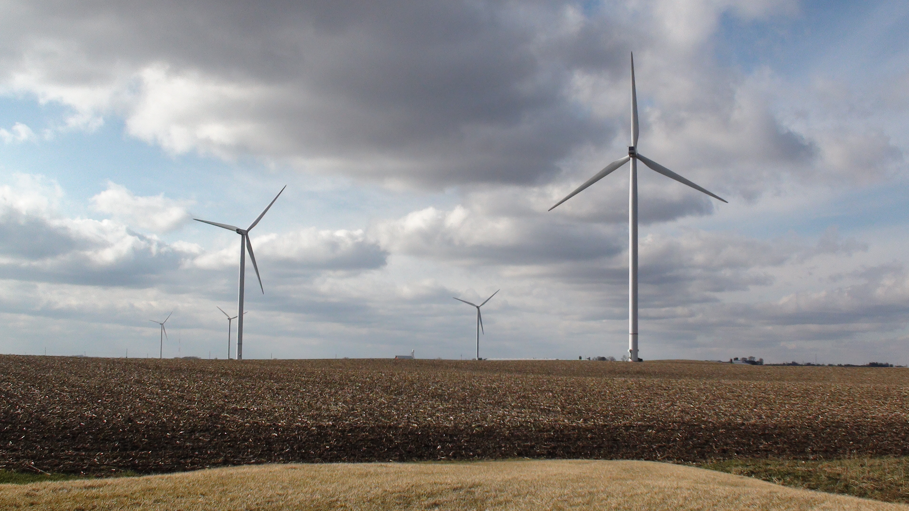 Three wind turbines in prairie with blue sunny sky and clouds
